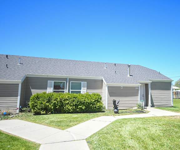the front of a gray house with a yard and a sidewalk