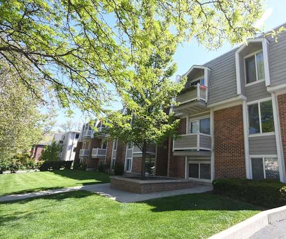 the exterior of an apartment building with a lawn and trees