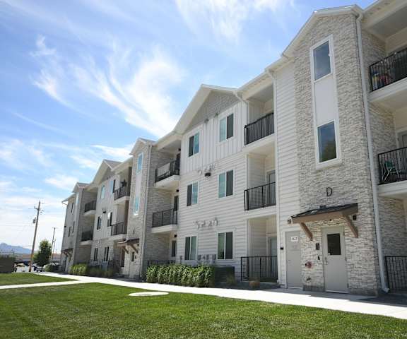 a row of white apartment buildings with balconies and a lawn