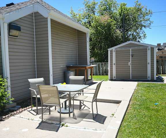 a backyard patio with a table and chairs and a shed