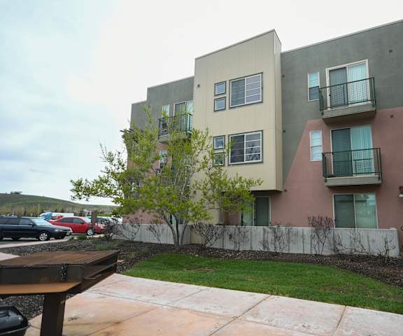 an exterior view of an apartment building with a yard and a sidewalk