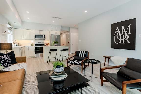 A modern living room with a black coffee table and a large artwork on the wall.