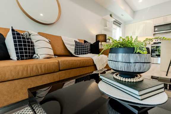 A living room with a brown couch and a black and white vase on the coffee table.