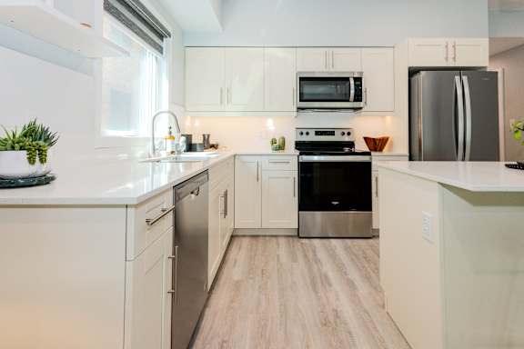 A modern kitchen with stainless steel appliances and wooden floors.