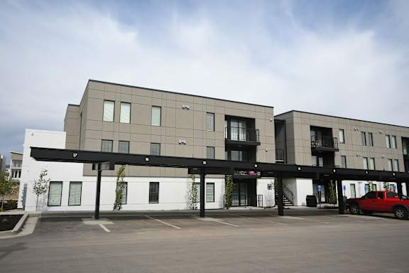 an apartment building with a parking lot and a red car