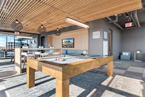 A pool table is in the middle of a room with a wooden ceiling.