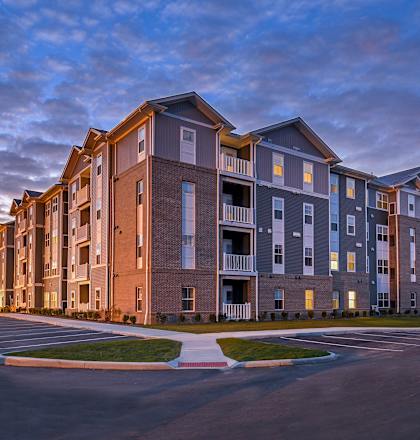 a large apartment building with a sunset in the background