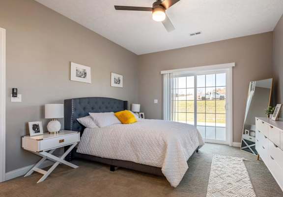 A bedroom with a bed, nightstand, and a ceiling fan.