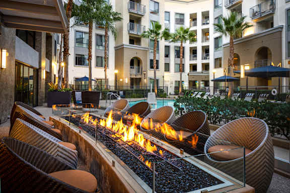 A fire pit in the middle of a courtyard surrounded by chairs.