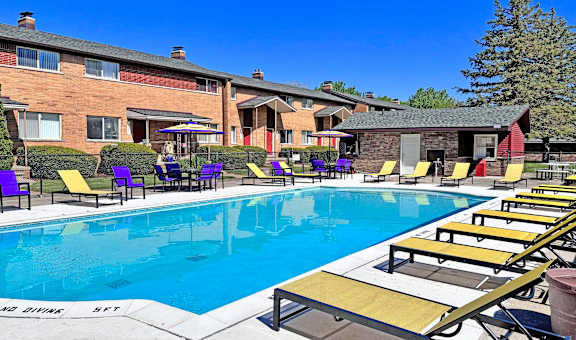A swimming pool with sun loungers and a building in the background.