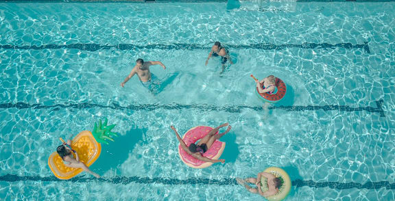 People are swimming in a pool with floaties.