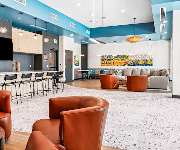 A modern lounge area with orange chairs and a white and blue color scheme.