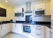 Thumbnail 5 of 5 - a kitchen with black counter tops and white cabinets