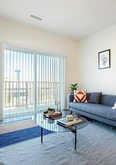 A living room with a grey couch, a coffee table, and a lamp.