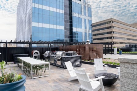 a patio with a table and chairs and a grill on a roof