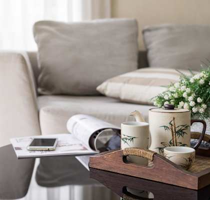 A modern living room with a grey couch, a round table, and a lamp.