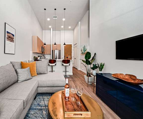 A modern living room with a grey sofa, a wooden coffee table, and a TV on the wall.