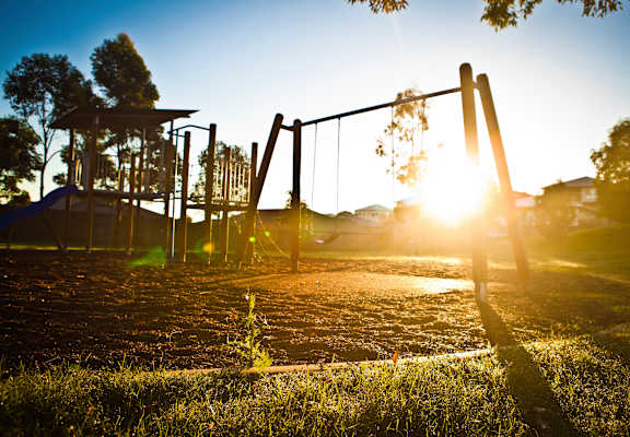 A playground with swings and a slide is bathed in sunlight at Pleasantview Apartments, Maryland