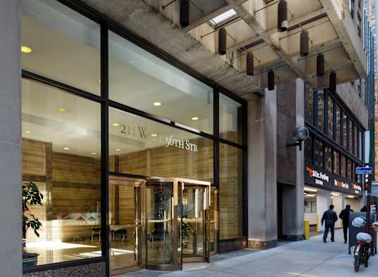 The entrance to a building with a glass door and a sign that reads "21 W 57th St".