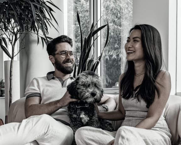 a black and white photo of a couple sitting on a couch with their dog