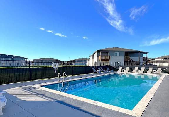 a swimming pool with chairs around it in front of a house