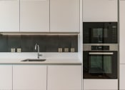 Thumbnail 1 of 7 - a kitchen with white cabinets and a black microwave and a sink