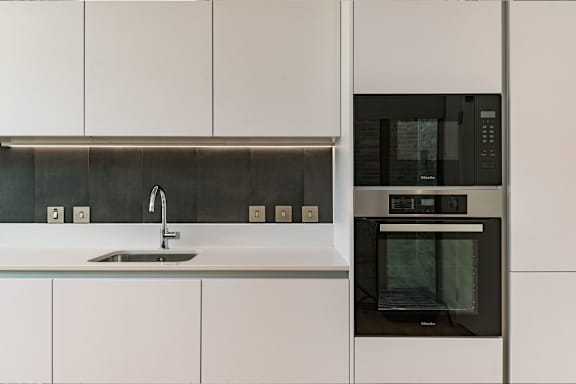 a kitchen with white cabinets and a black microwave and a sink