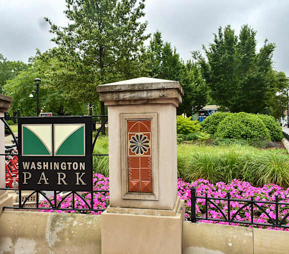 A sign that says Washington Park is on a black fence.