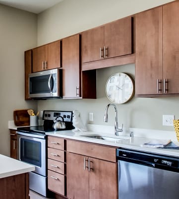 an apartment kitchen with stainless steel appliances and wooden cabinets