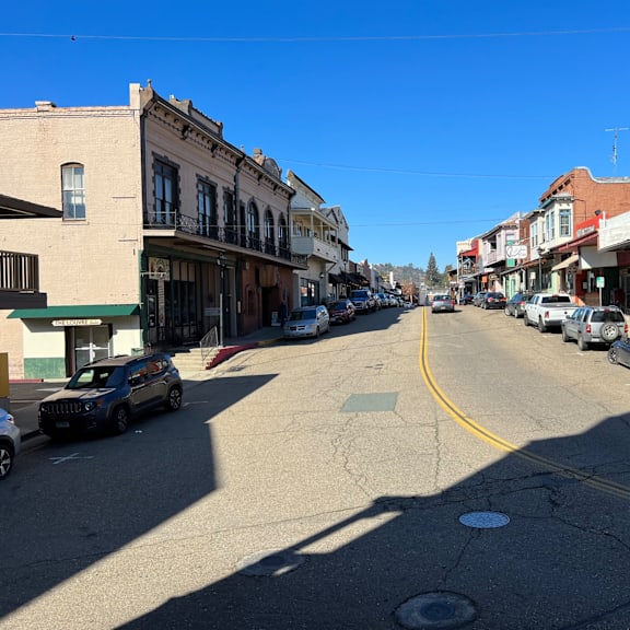 A street in a small town with cars parked on the side.