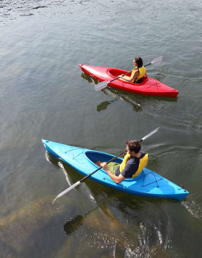 two people in kayaks on the water at Vibe Apartments at Arbour Lake, Calgary