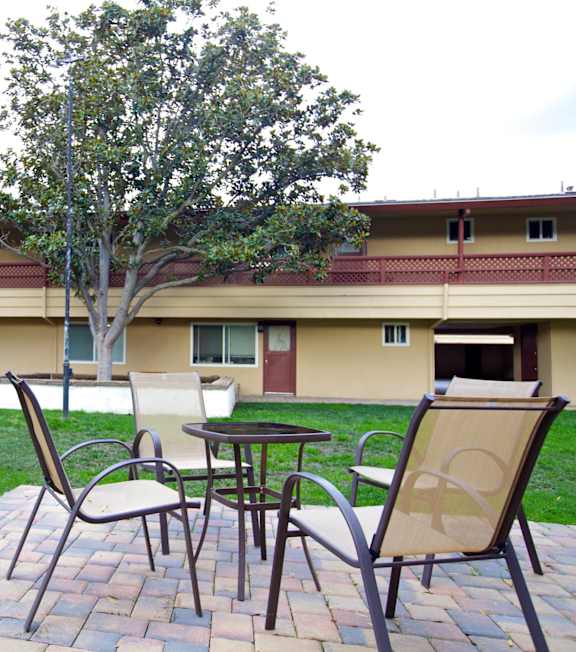 a patio with chairs and a table in a courtyard