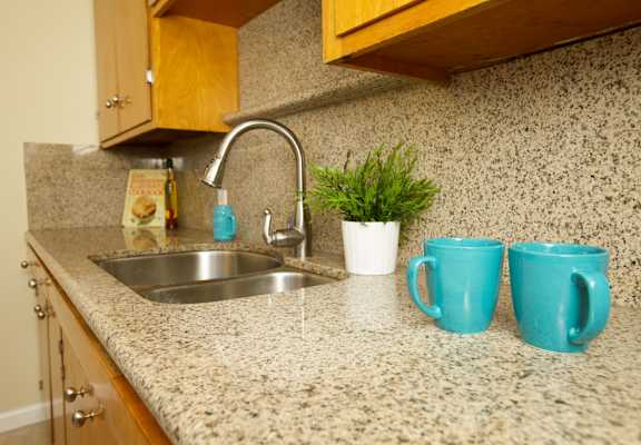 a kitchen counter with two blue mugs and a sink