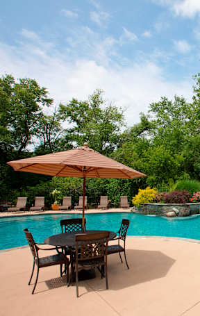 A pool with a table and chairs and umbrellas. at Rivercrest Apartments, New Jersey, 08854