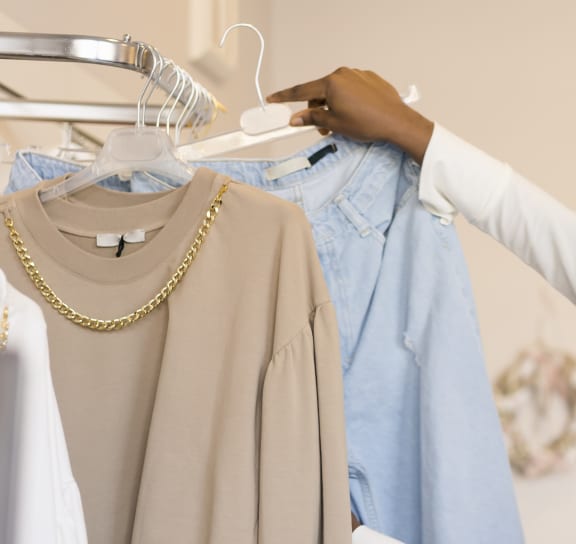 a woman in a white shirt holding up a blue shirt on a hanger