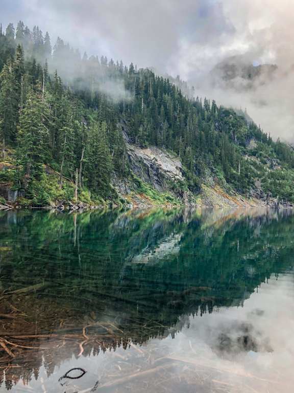 a lake in the mountains with the reflection of the trees in the water