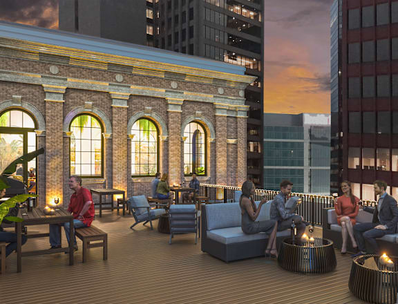A group of people are sitting and talking on a rooftop patio.