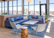 Thumbnail 6 of 11 - a living room with blue couches and white chairs with a view of the city in the