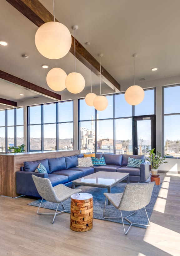 a living room with blue couches and white chairs with a view of the city in the