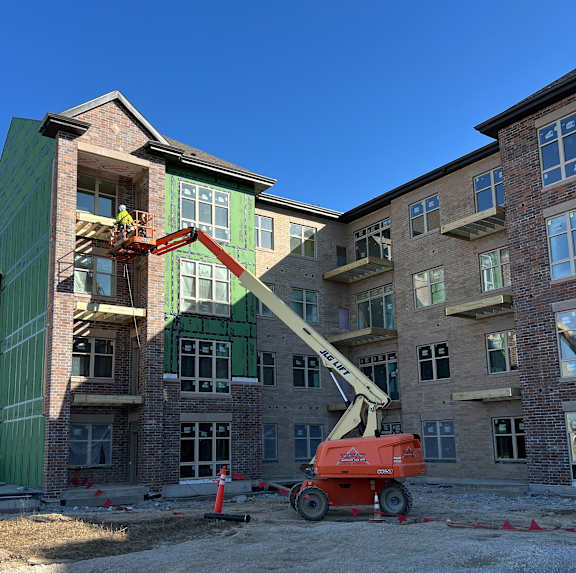 A construction site with a red cherry picker and a building under construction.