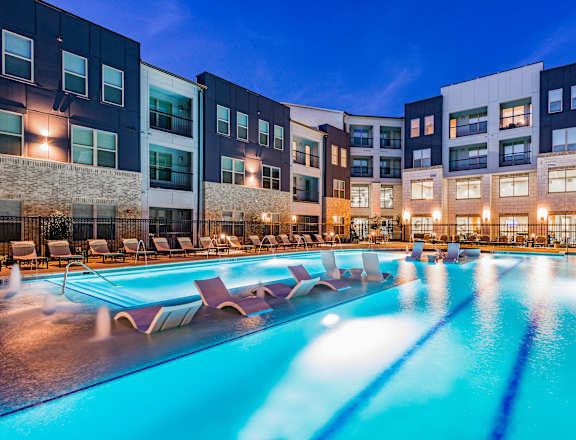 a swimming pool with chaise lounge chairs in front of a building