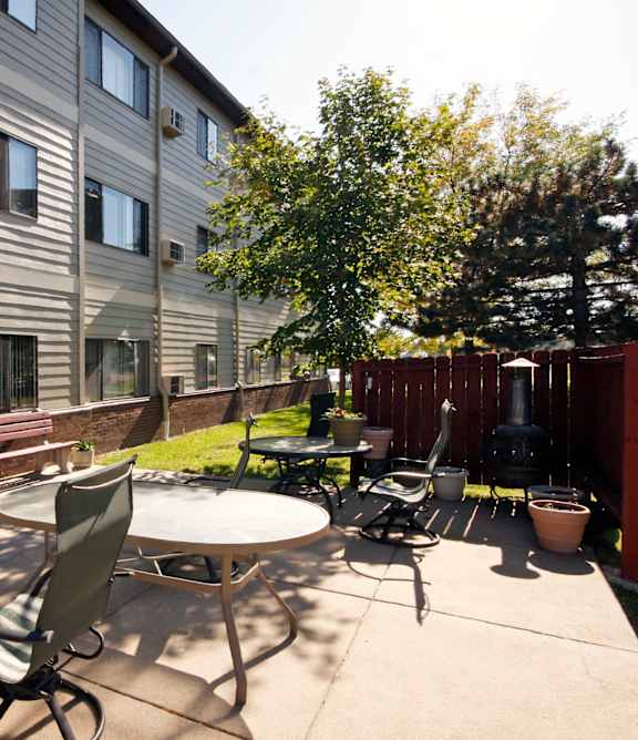 A patio with a table and chairs is in front of a building.