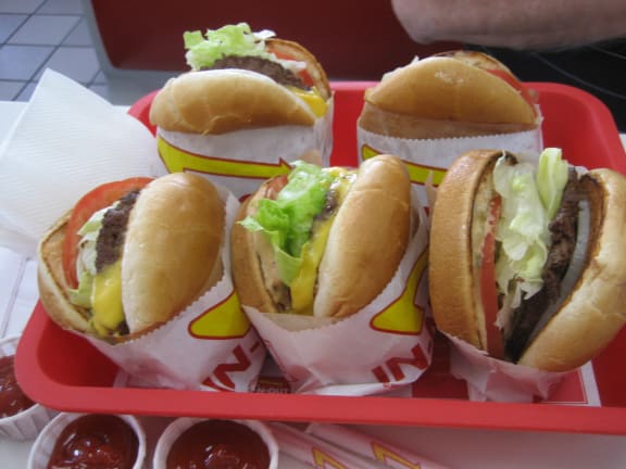 four hamburgers in a red tray with ketchup