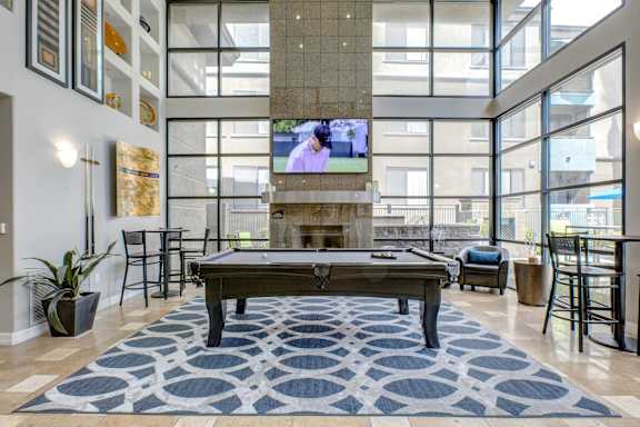 A pool table in a room with a television and a large window.