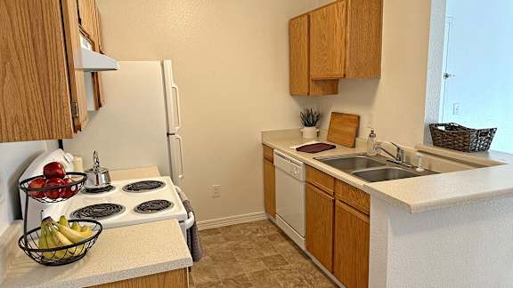 Bridgeside Landing Apartments in Taylorsville, Utah, Kitchen with wood cabinets, stove, fridge, dishwasher and double sink.