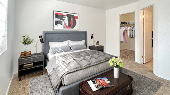 Bridgeside Landing Apartments in Taylorsville, Utah, large double bed with two nightstands, grey bedding, walk-in closet.