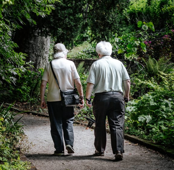 an older couple walking down a path in a park
