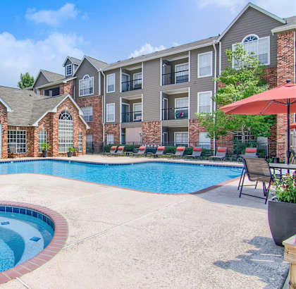 A pool surrounded by a patio with chairs and umbrellas.