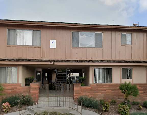 the front of a brown building with a porch and a staircase