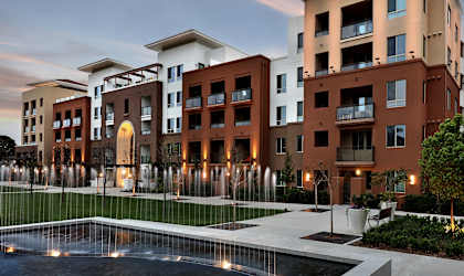 A modern apartment complex with a pool in the foreground.
